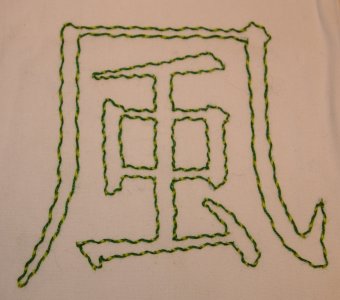 Beispiel für umschlungenen Vorstich: Das Kanji für Wind in hellgrünem Vorstich, umschlungen in Dunkelgrün. Vorlage in Pinselschrift.